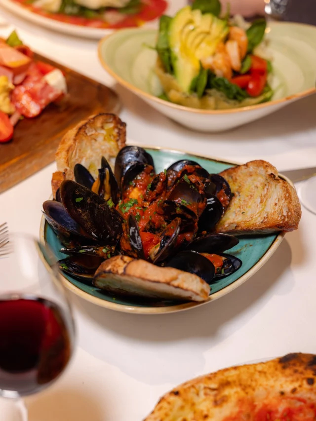 Mejillones, salsa para mojar, pan para repetir
y más platos esperando en la mesa.

Así da gusto sentarse.